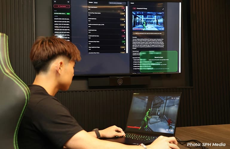 Person using a laptop to interact with an AI-powered software platform, while a large display shows real-time issue tracking, analysis, and application performance dashboards.