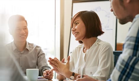 Three colleagues having a discussion in a meeting room.