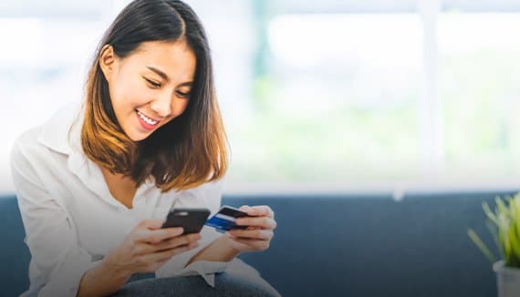 Woman using a smartphone and holding a card