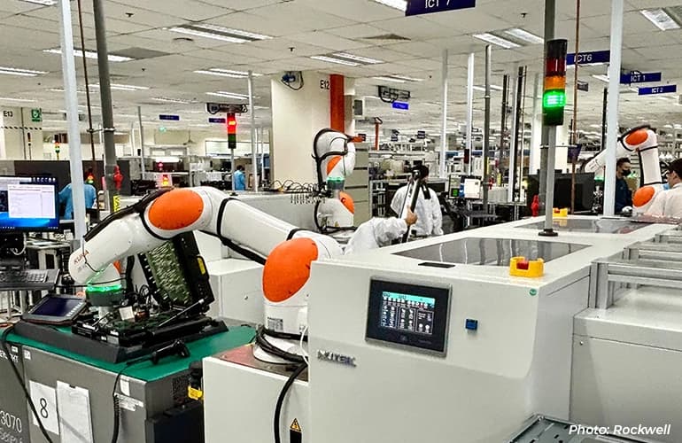 Robotic arms operating automated equipment inside a manufacturing facility.