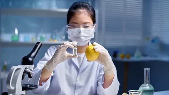 Scientist in a lab examining a lemon and a vial of liquid