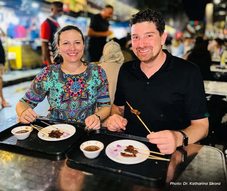 Katharina and her husband at a hawker centre enjoying local food.