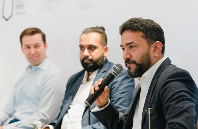 Three men in business attire on a panel discussion