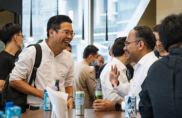 Two men in business casual attire chatting and smiling