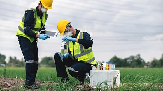 Workers in safety gear testing bio-based chemicals in a field