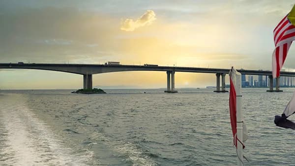 View of a bridge over water at sunset with a Malaysian flag