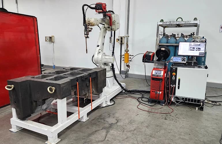Robotic welding arm set up with industrial equipment inside a manufacturing facility.