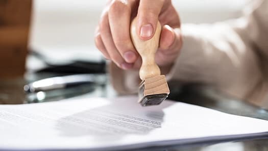 Hand stamping an official document with a rubber stamp.
