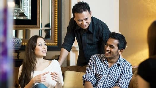 Three friends chatting and laughing in a living room.