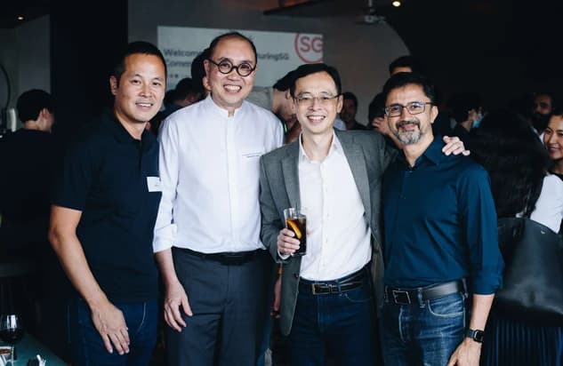 Four men smiling together at a casual social gathering