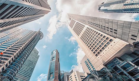 Upward view of skyscrapers against a blue sky, representing Singapore's financial district.