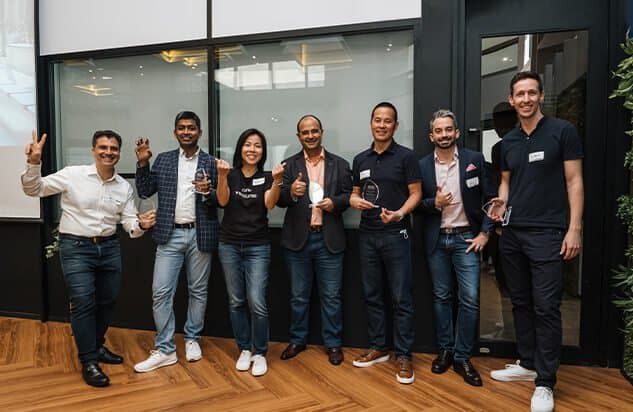 Group of seven people smiling while holding plaques in an indoor setting