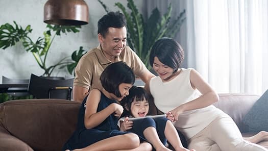 Family using a tablet together on a living room sofa.