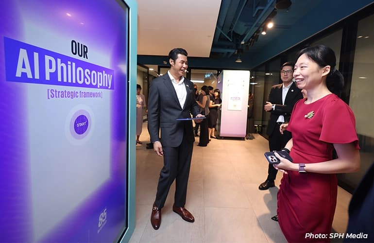 Visitors interact with an AI philosophy display at a technology showcase, as attendees network and explore digital innovation exhibits in a modern office space.