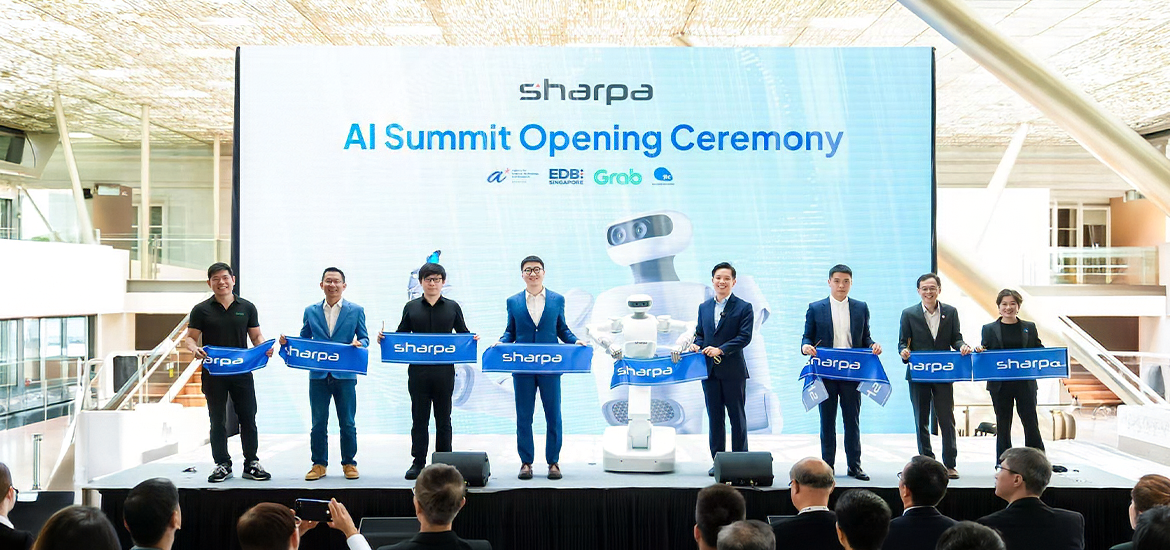 Officials and industry representatives stand on stage holding ceremonial banners during the Sharpa AI Summit Opening Ceremony. A large digital backdrop displays event branding, partner logos, and a humanoid robot, while attendees watch from the audience.