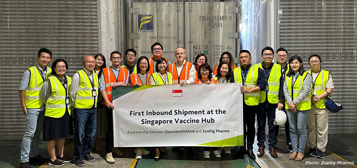 Group photo of staff in safety vests holding a banner reading 'First Inbound Shipment at the Singapore Vaccine Hub – A partnership between GlaxoSmithKline and Zuellig Pharma'