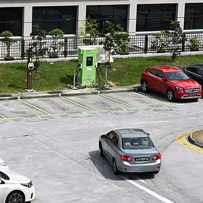 Electric vehicle charging stations in a parking lot, with cars parked and charging points marked in green.