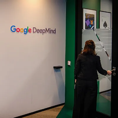 Entrance to a Google DeepMind office with people walking in a hallway.