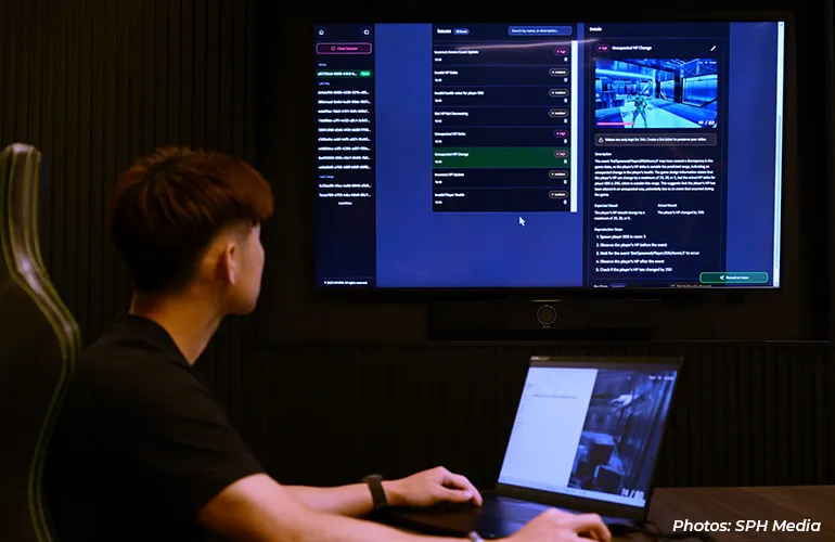Person reviewing data and dashboards on a large screen with a laptop in a control room.