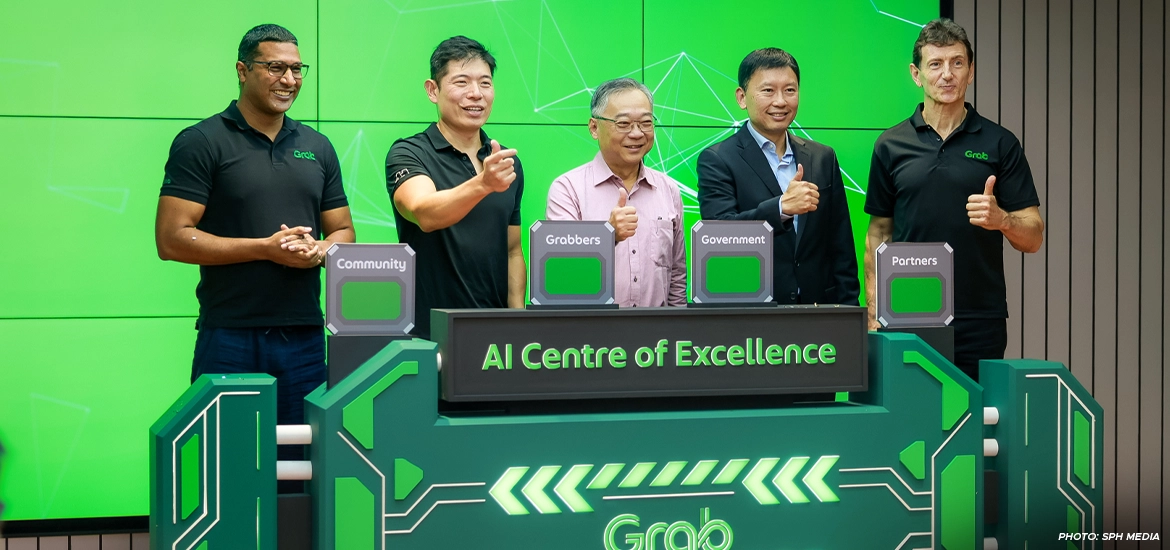 Group of five men giving thumbs up at the launch of Grab's AI Centre of Excellence, standing in front of a vibrant green digital-themed backdrop with labeled pillars for Community, Grabbers, Government, and Partners.