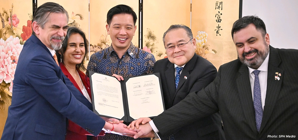 Group of business and government representatives celebrating the signing of a partnership agreement, symbolizing international collaboration and strategic cooperation.