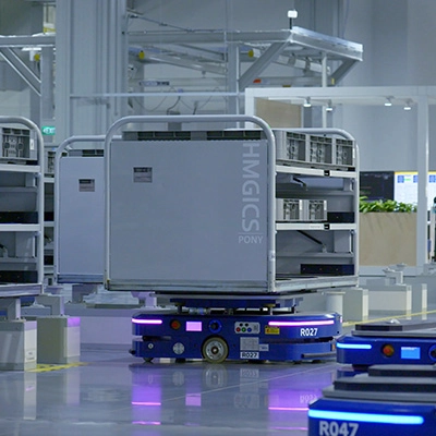 Autonomous mobile robots transporting storage racks inside a high-tech manufacturing facility at Hyundai Motor Group Innovation Center Singapore.