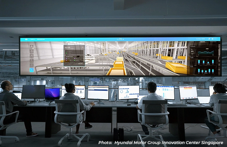 Engineers monitoring production systems in a digital command center, with multiple workstations and a large real-time dashboard displaying factory operations at Hyundai Motor Group Innovation Center Singapore.