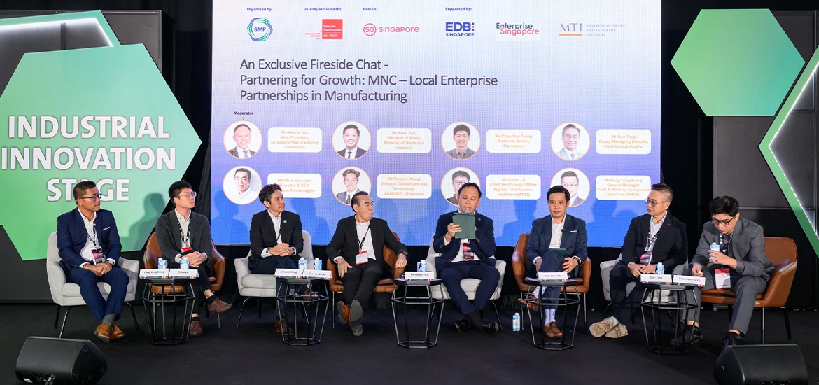 Panel discussion on industrial innovation, featuring business leaders speaking on manufacturing partnerships at a conference stage.