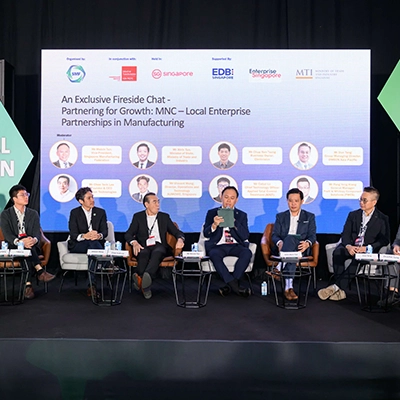 Panel discussion on industrial innovation, featuring business leaders speaking on manufacturing partnerships at a conference stage.