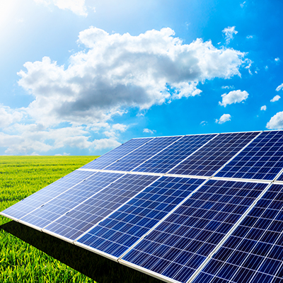Solar panels installed in an open field under a bright blue sky, generating renewable energy through sustainable solar power technology.