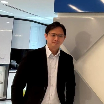 A man in business attire standing beside a wall with the Haier company logo inside a modern office setting..