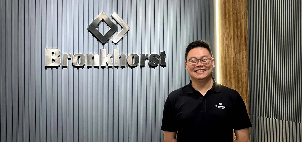 Man standing and smiling in front of a wall with the Bronkhorst company logo.