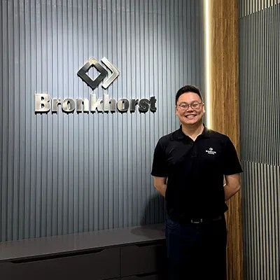 Man standing and smiling in front of a wall with the Bronkhorst company logo.