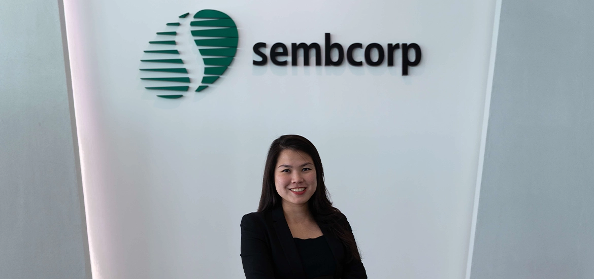 Woman standing beside Sembcorp Banyan Energy Storage System containers at an industrial site.