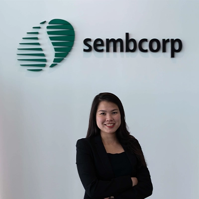 Woman standing beside Sembcorp Banyan Energy Storage System containers at an industrial site.