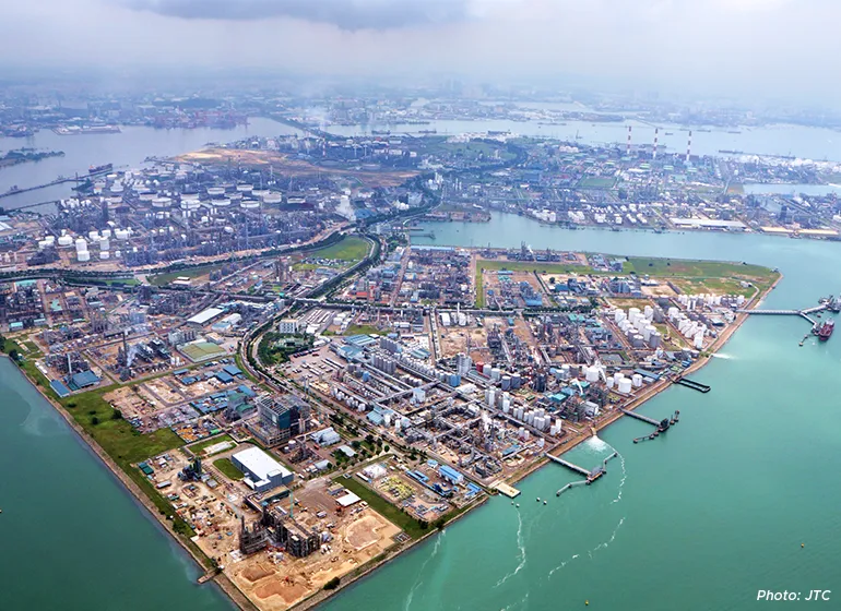 Aerial view of Singapore’s Jurong Island industrial hub featuring petrochemical plants, storage tanks, manufacturing facilities, and port infrastructure surrounded by coastal waters.