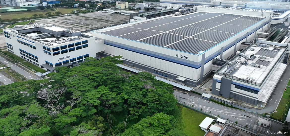 Micron semiconductor manufacturing facility in Singapore, featuring large cleanroom buildings and rooftop solar panels surrounded by greenery.