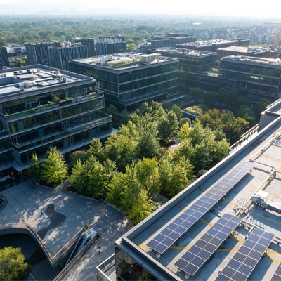 Aerial view of a modern office campus with green courtyards and rooftop solar panels.