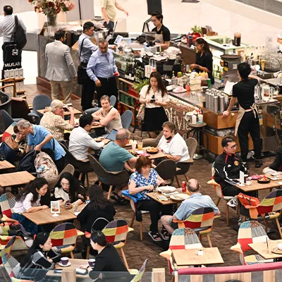 Busy café scene with diners enjoying food and drinks in a vibrant indoor dining area.
