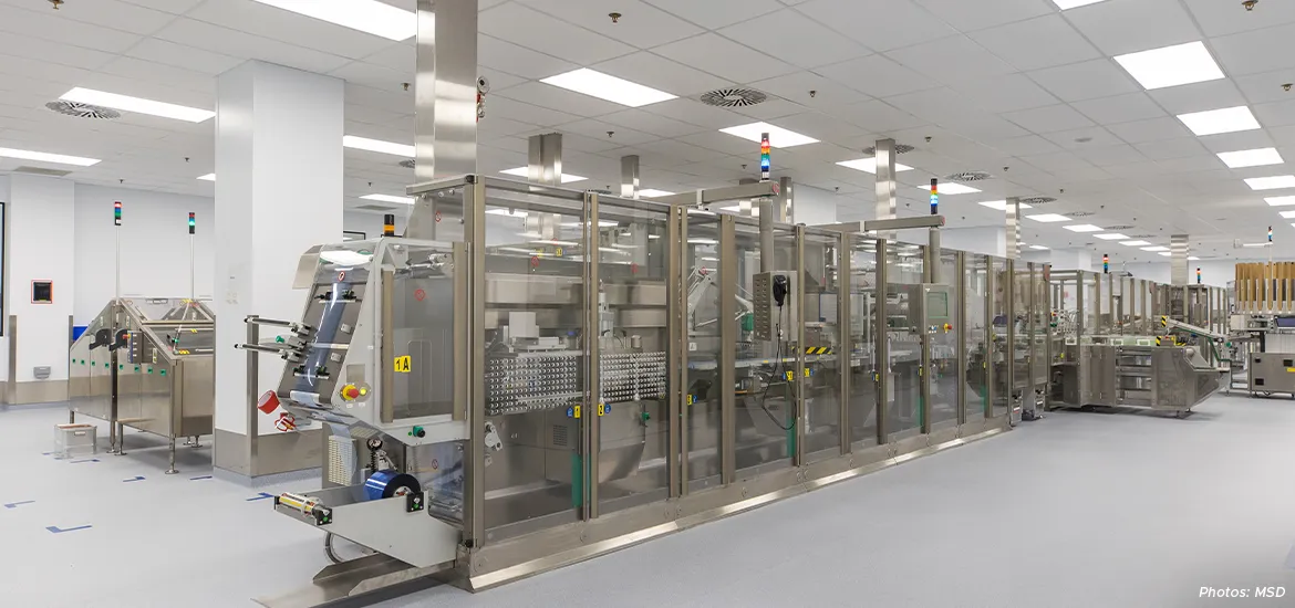Modern pharmaceutical manufacturing facility with automated sterile processing and packaging equipment inside a cleanroom environment.