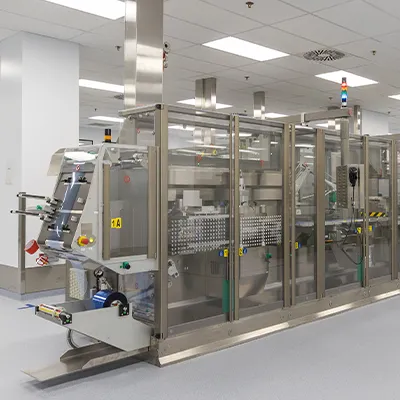 Modern pharmaceutical manufacturing facility with automated sterile processing and packaging equipment inside a cleanroom environment.