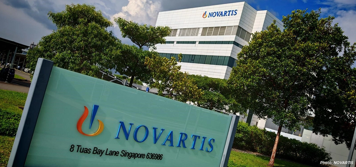 Novartis Singapore facility exterior with company signage at 8 Tuas Bay Lane, surrounded by greenery and modern office architecture.