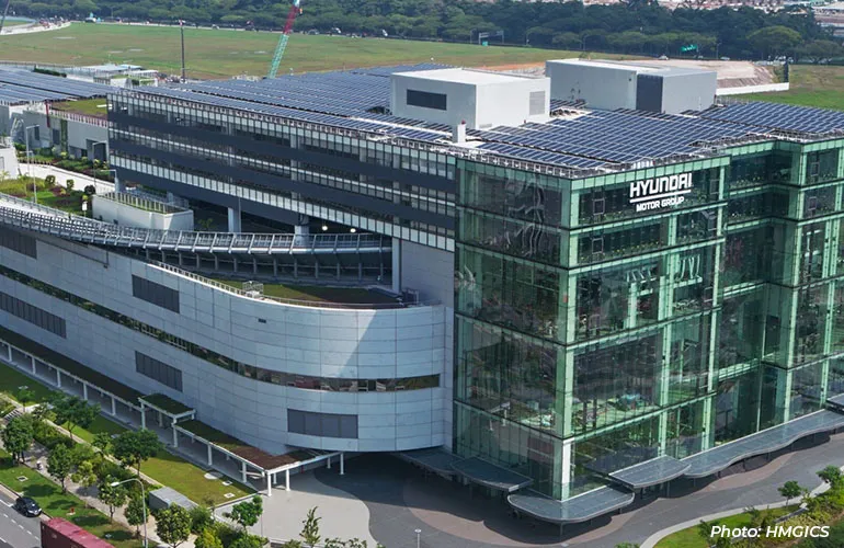 Aerial view of a large modern industrial or research facility with a curved building design and rooftop greenery.