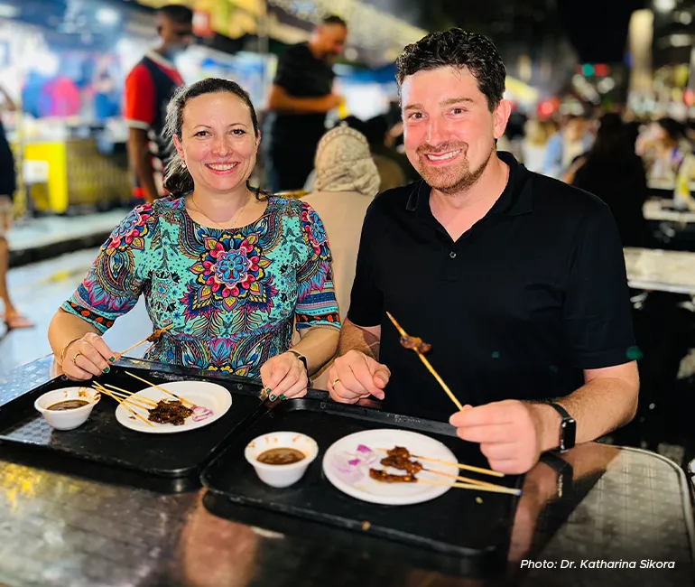 Katharina and her husband at a hawker centre enjoying local food. 
