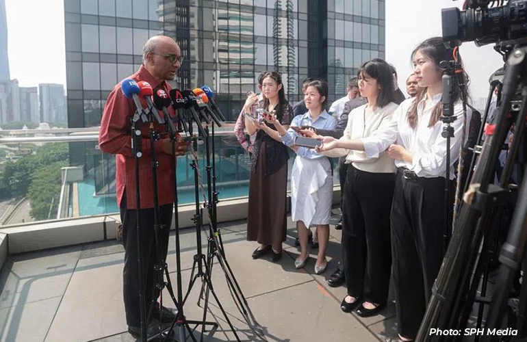 Man speaking to reporters during an outdoor media briefing.