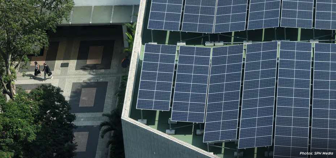 Aerial view of rooftop solar panels on a Singapore building, showcasing urban renewable energy adoption with pedestrians walking below.