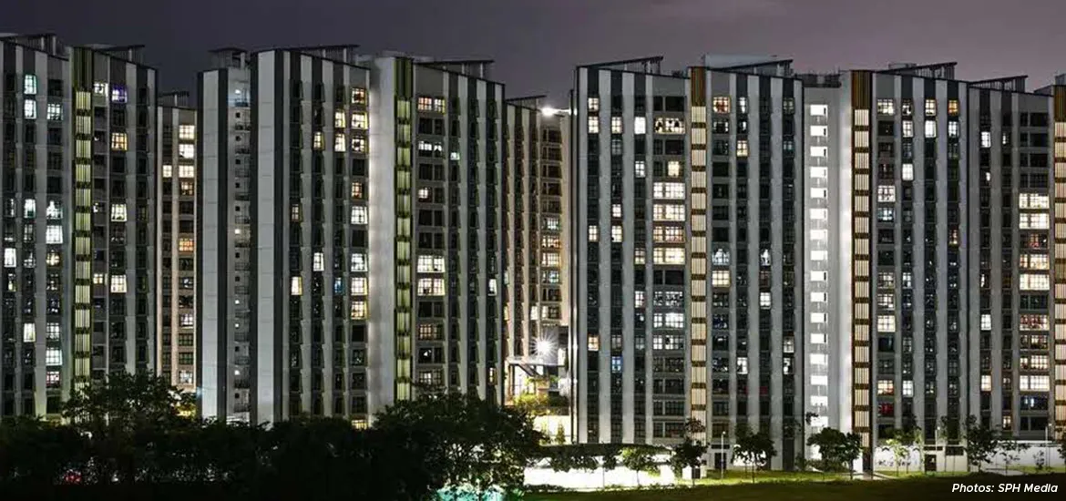Night view of Singapore HDB public housing blocks with illuminated windows, showcasing urban living and high-rise residential architecture.