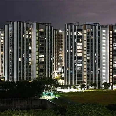 Night view of Singapore HDB public housing blocks with illuminated windows, showcasing urban living and high-rise residential architecture.