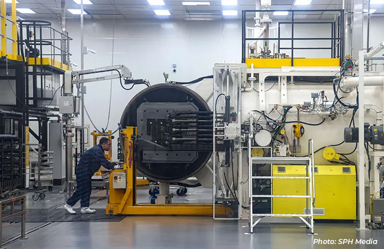 Technician operating a large industrial vacuum or pressure chamber inside a modern manufacturing facility.