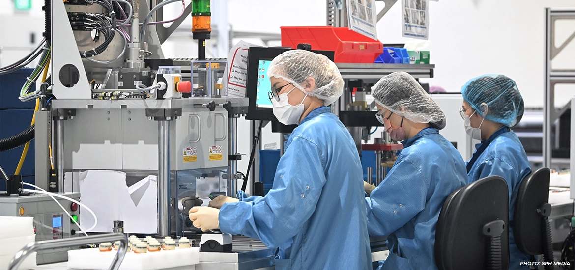 Workers in cleanroom suits operate precision machinery in a high-tech manufacturing facility, emphasizing sterile and controlled conditions.